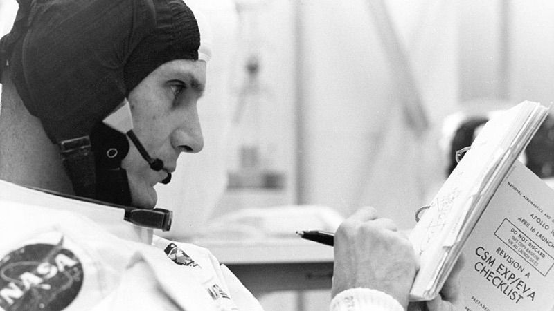 Apollo astronaut writing in a log book.